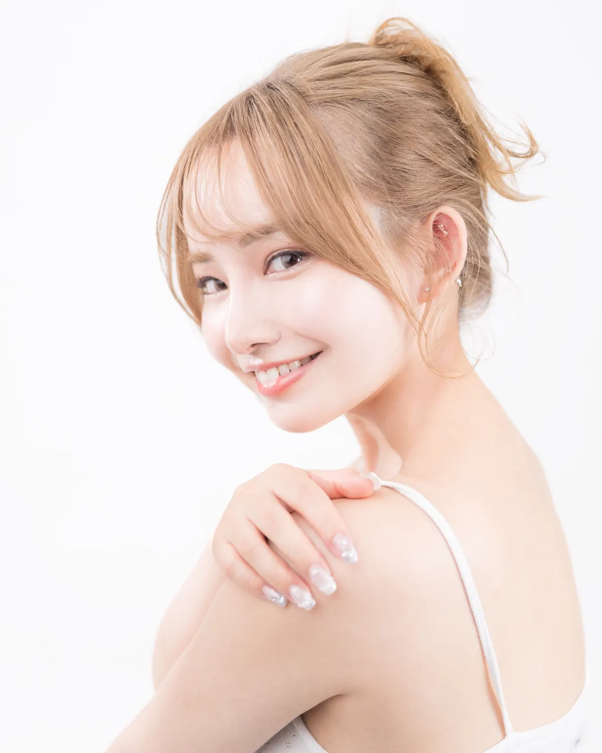 白を背景に、髪を後ろでまとめた女性モデルがこちらを向いている